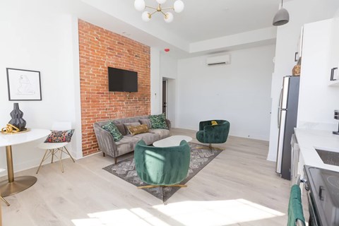 A living room with a brick wall and a grey couch.