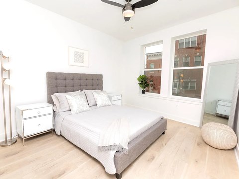 A bedroom with a bed, nightstand, and a plant on the windowsill.