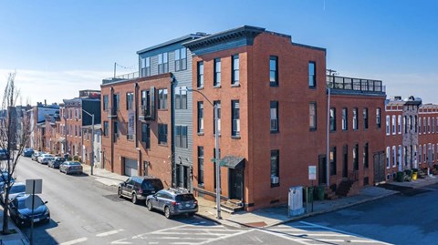 A street view of a row of buildings with cars parked on the side.