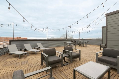 A rooftop patio with grey furniture and string lights.