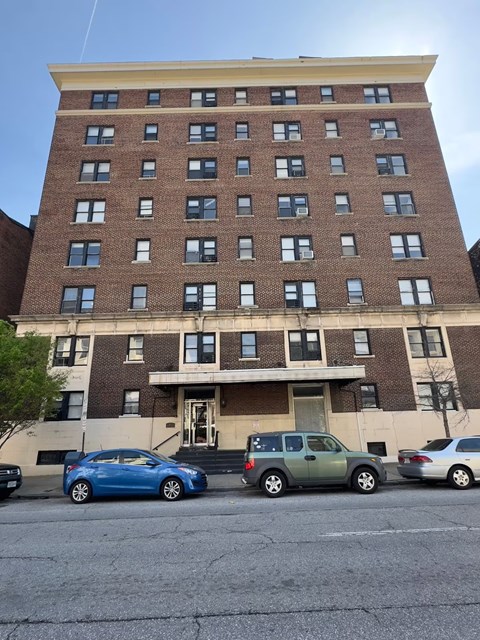 A blue car is parked in front of a brick building.