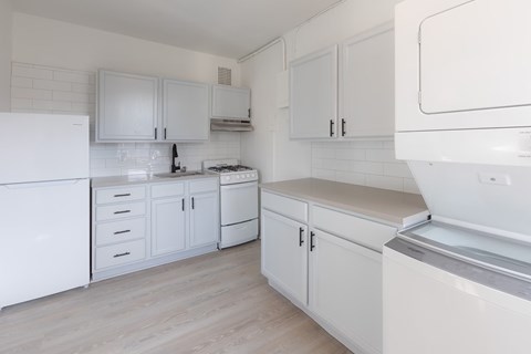 A white kitchen with a refrigerator, oven, and sink.