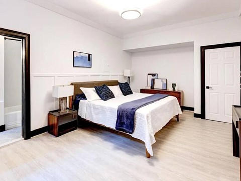 A bedroom with a bed, nightstand, and lamp.