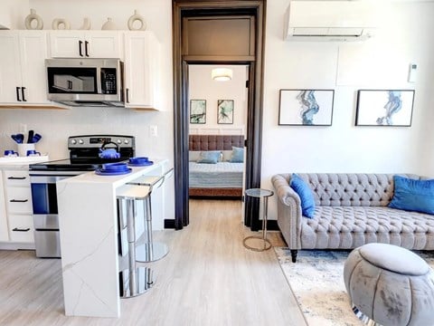 A modern kitchen with a grey couch and two framed pictures on the wall.