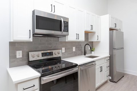 A modern kitchen with a stove, microwave, and refrigerator.