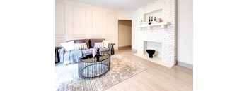 A living room with a white brick fireplace and a black coffee table.