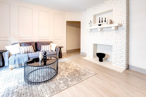 A living room with a white brick fireplace and a black coffee table.