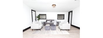 A living room with a grey sofa set and a grey ottoman.