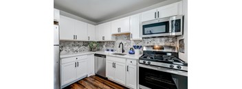 A kitchen with white cabinets and a black stove top.