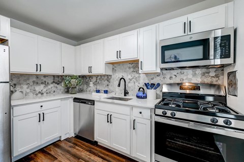 A kitchen with white cabinets and a black stove top.