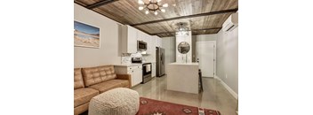 A modern kitchen with a brown leather couch and a rug on the floor.