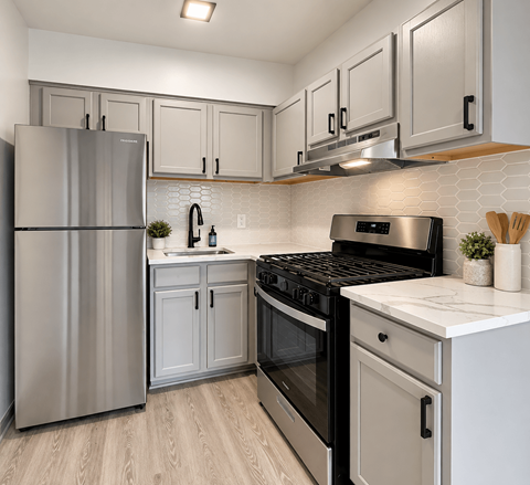 A modern kitchen with a stainless steel refrigerator, black stove, and white countertops.