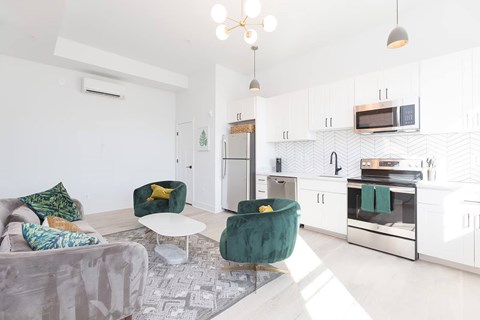 A modern kitchen with white cabinets and a green chair.