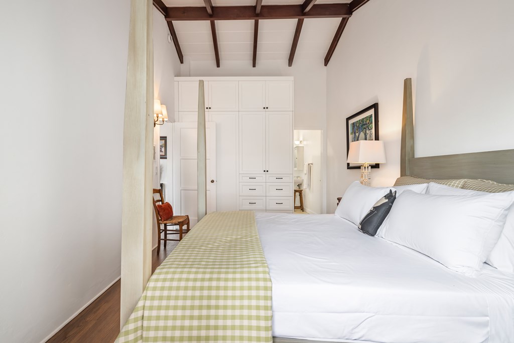 A bedroom with a bed, a chair, and a lamp.