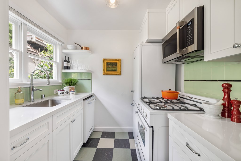 A kitchen with white cabinets and a black and white checkered floor.