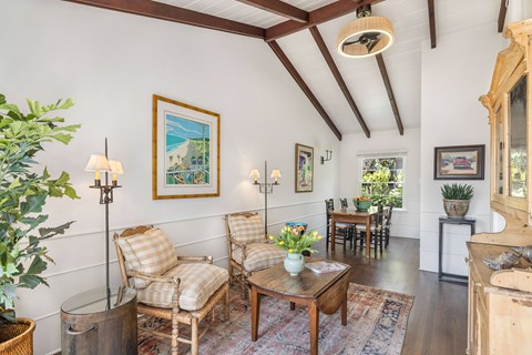 A living room with a wooden floor and a painting on the wall.