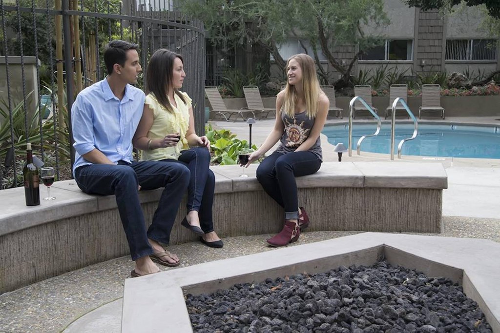 a group of people sitting on a ledge by a pool at The Aspens Fairhaven, Santa Ana California