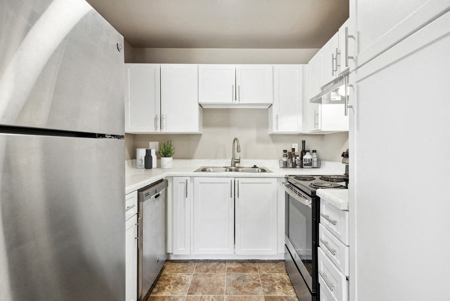an all white kitchen with stainless steel appliances and white cabinets