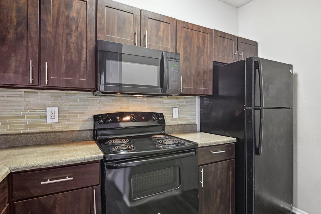 A kitchen with a black stove and refrigerator.