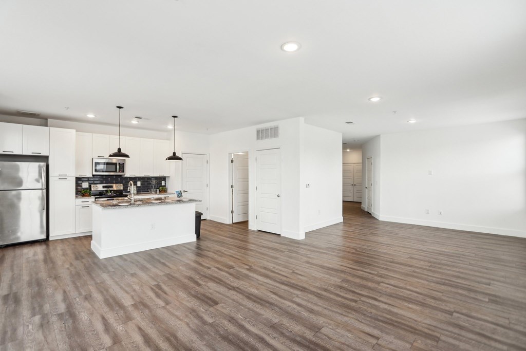 A modern kitchen with wooden floors and white cabinetry.