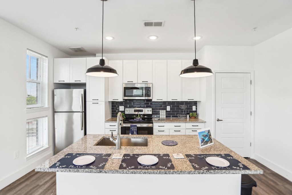 A modern kitchen with a granite countertop and stainless steel appliances.