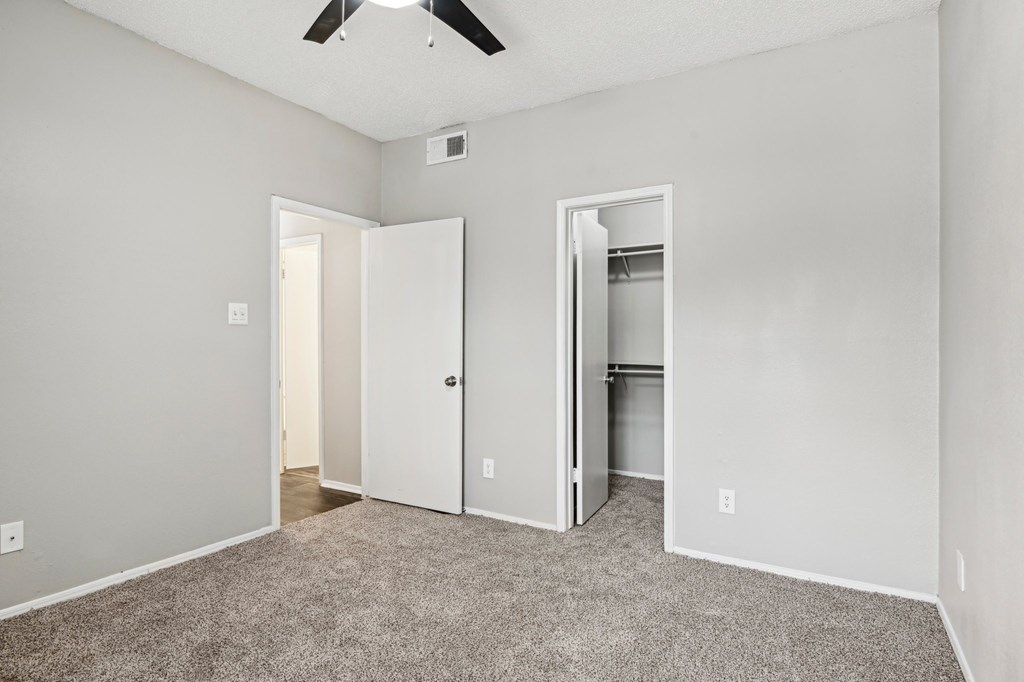 A room with a ceiling fan and two doors, one of which is open.