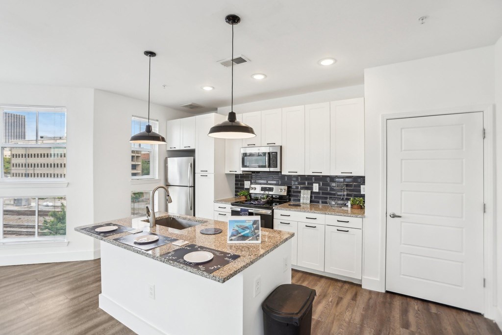A kitchen with white cabinets and a granite countertop.