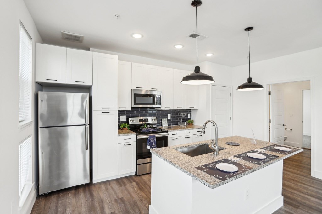 A modern kitchen with a granite countertop and stainless steel appliances.