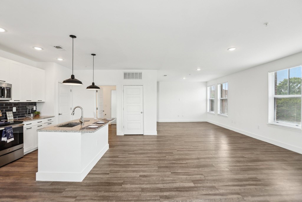 A modern kitchen with wooden floors and white cabinetry.