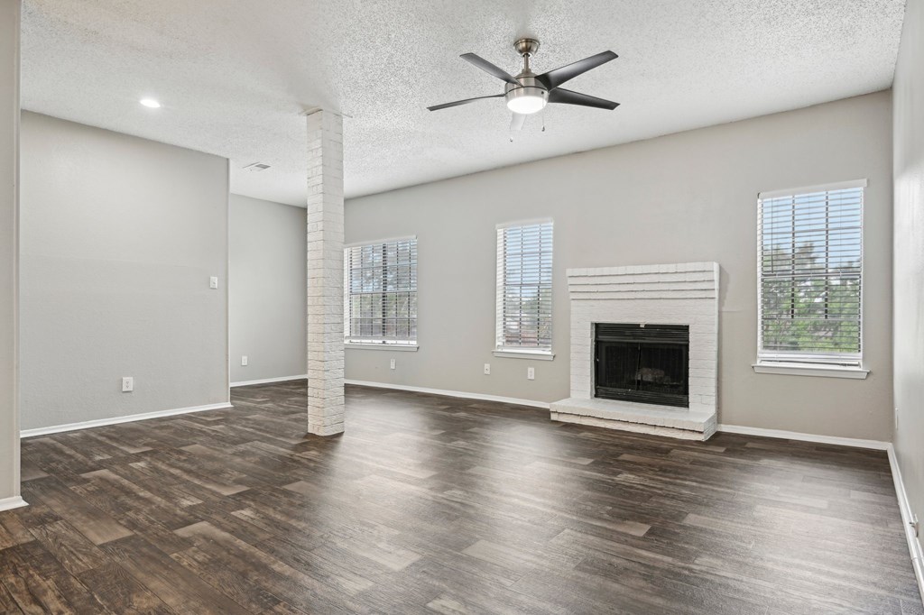 A spacious living room with a fireplace and wood flooring.