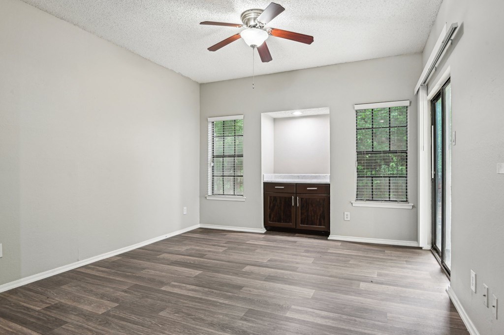 A room with a ceiling fan and wooden flooring.