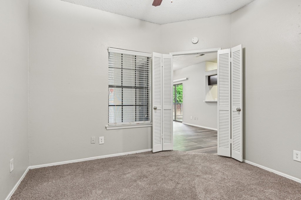 A room with a carpeted floor and a window with blinds.
