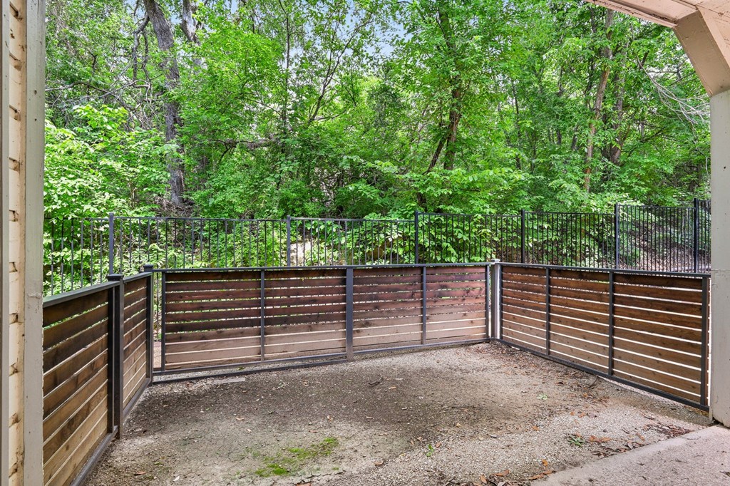 A backyard with a wooden fence and a dirt area in the middle.