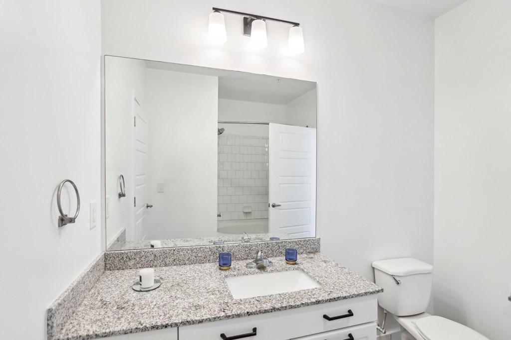 A bathroom with a granite countertop and white fixtures.