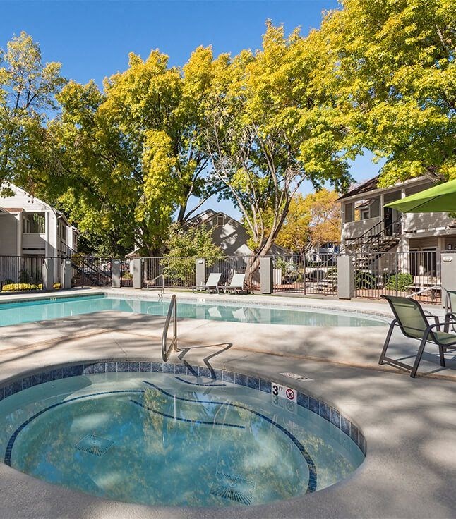 a swimming pool with a hot tub and a patio with chairs