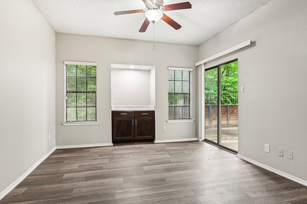 A room with a ceiling fan and sliding glass doors.