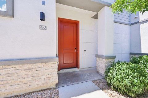 Baseline on 16th townhome red door is the entrance to a house with a stone wall.