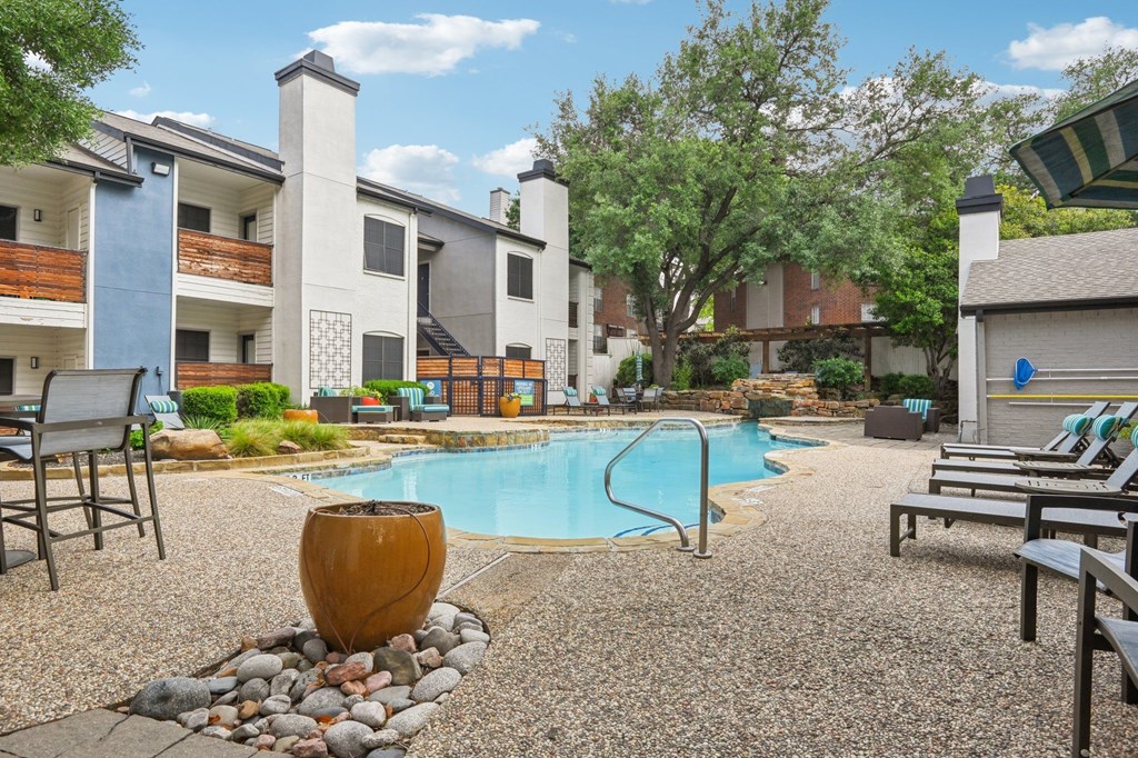 A pool surrounded by chairs and a large vase.