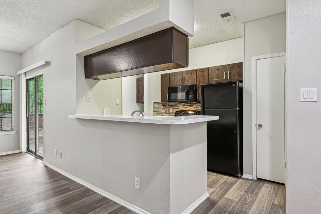 A kitchen with a black refrigerator and a white counter.
