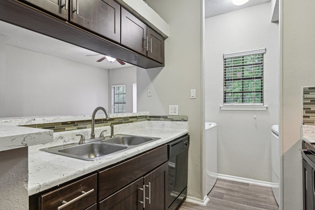 A kitchen with a marble countertop and dark wood cabinets.