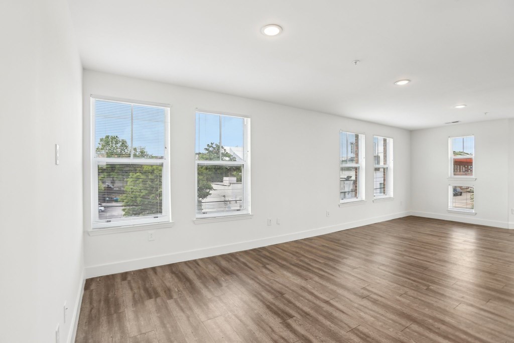 A large empty room with wooden floors and windows.