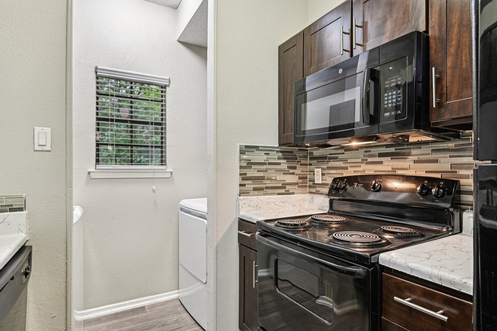 A kitchen with a black stove top oven and a black microwave above it.