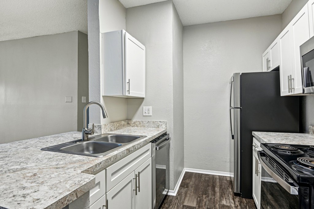 A kitchen with a black refrigerator and white cabinets.