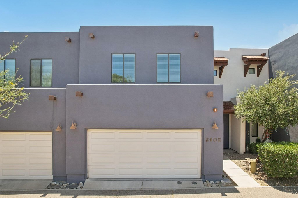 A modern house with a grey facade and white garage doors.