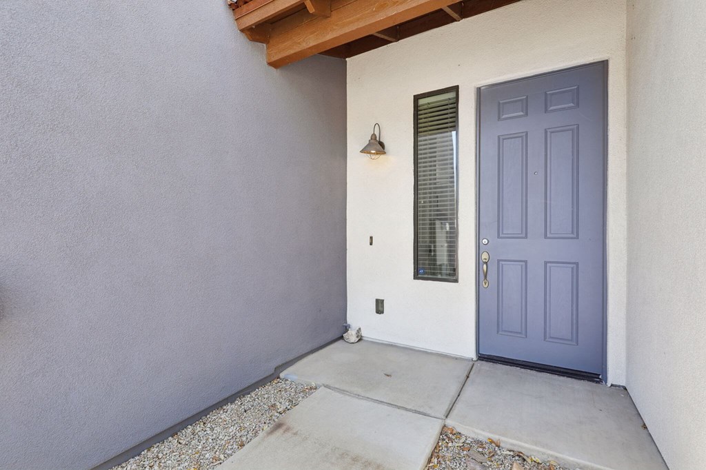 A blue door is on the right side of a white wall.