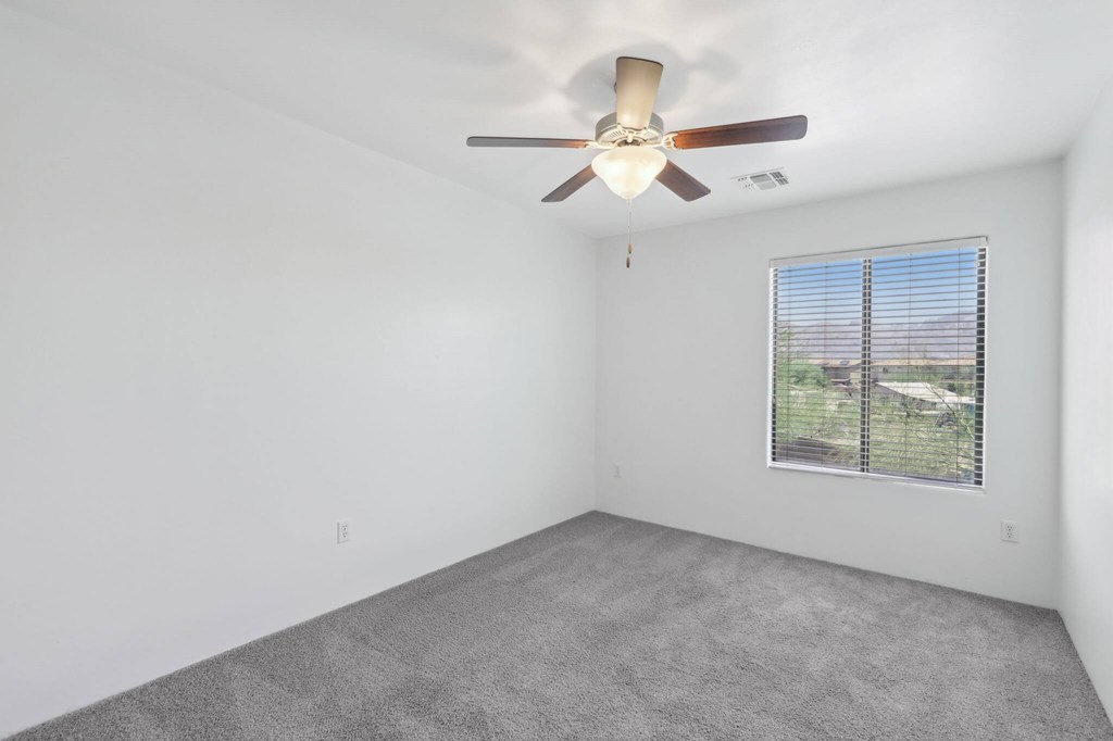 Bedroom with a ceiling fan and a window overlooking a fence.