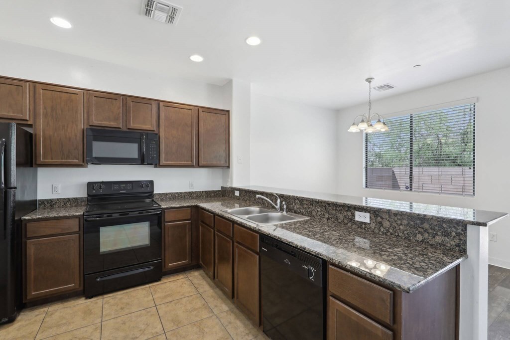 A kitchen with dark wood cabinets and black appliances.
