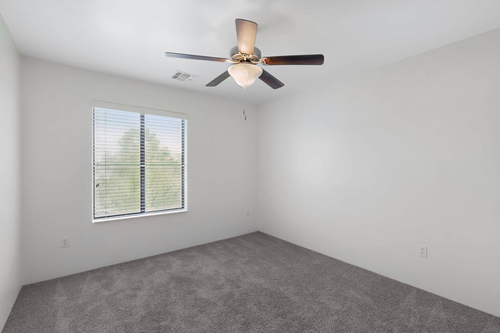 A room with a ceiling fan and a window with blinds.