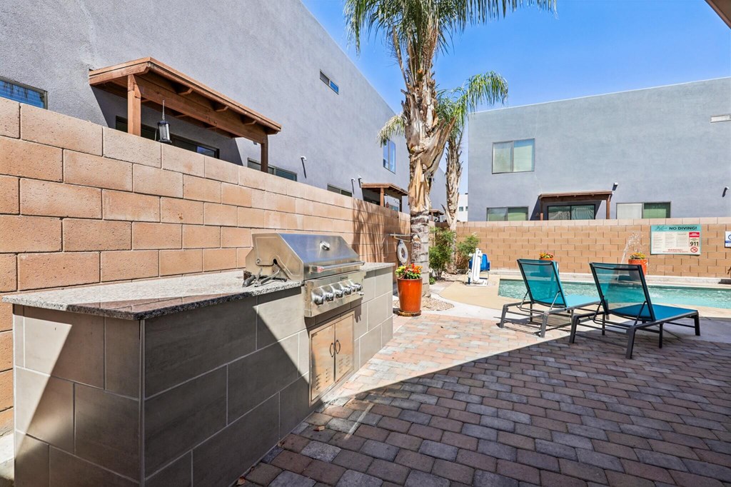 A modern outdoor kitchen area with a grill and seating area.