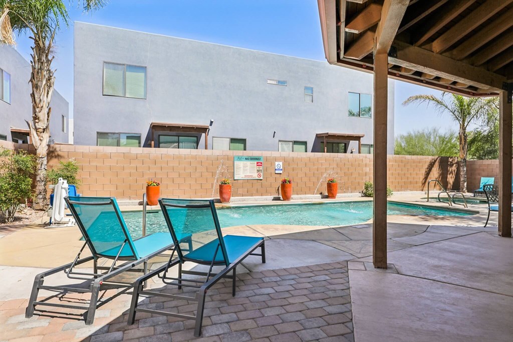 A pool area with two chairs and a building in the background.